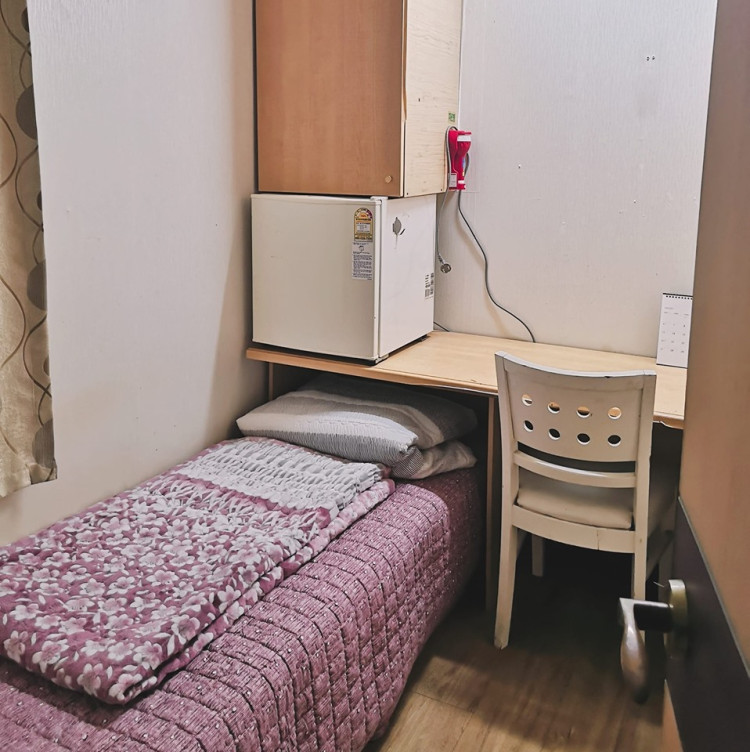 Phòng trọ nhỏ với giường, tủ lạnh, bàn học và kệ đựng đồ.