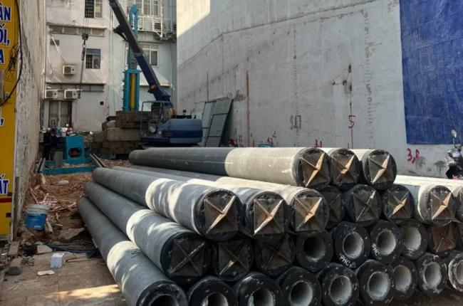 Công trường xây dựng với cẩu trục và các ống bê tông lớn.